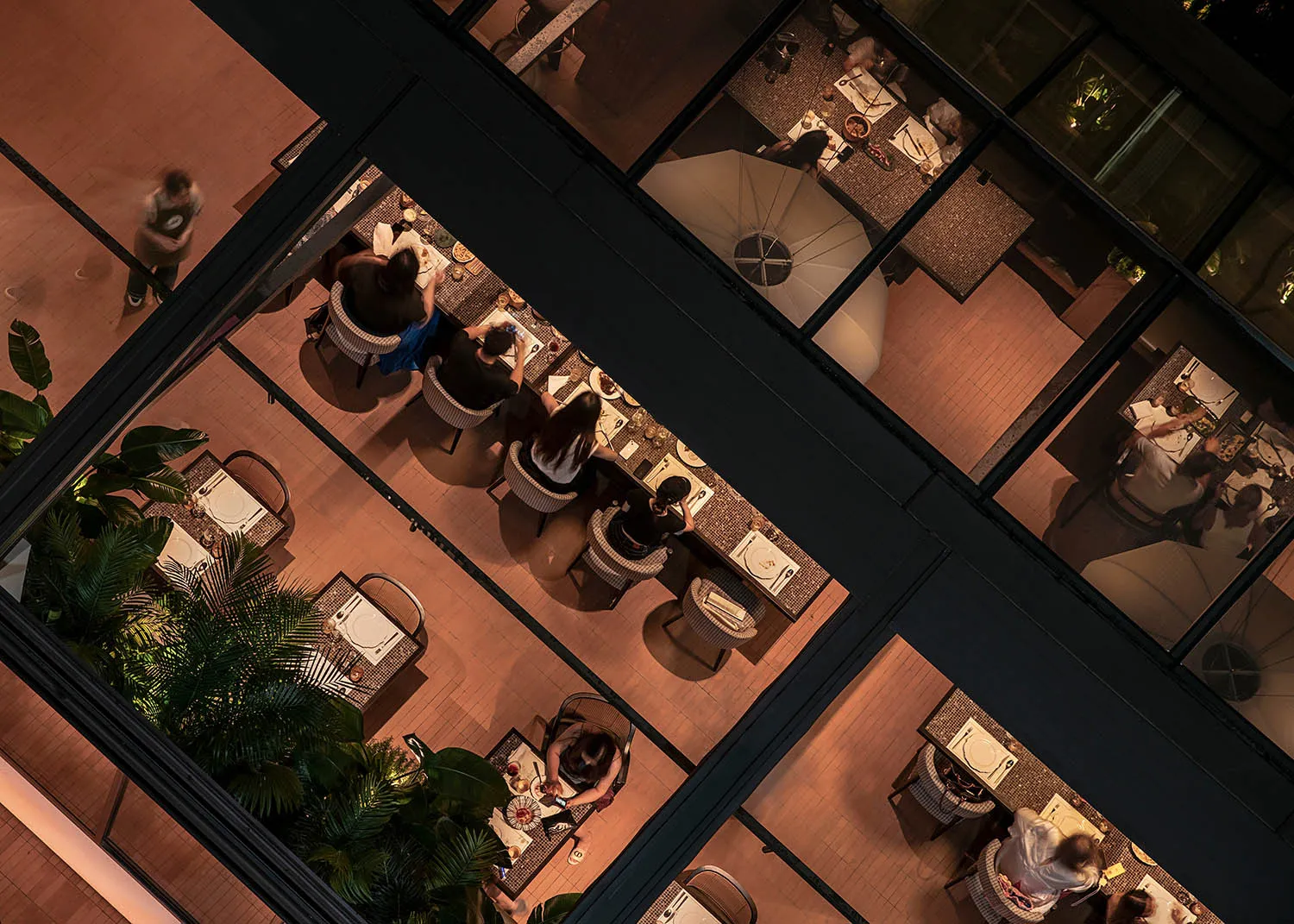 People sitting at tables in a restaurant with tile flooring and modern furniture.