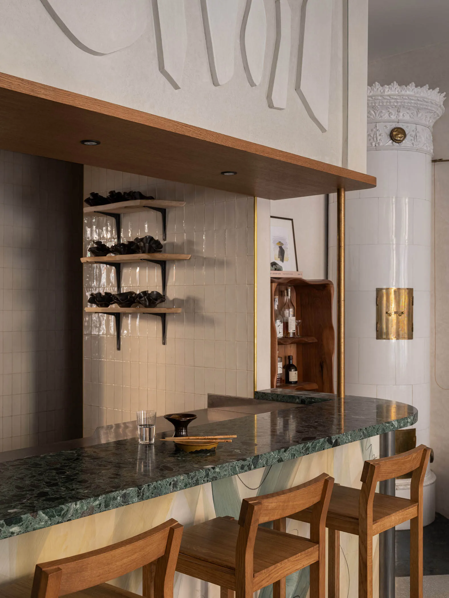 Modern restaurant interior with a polished marble counter and wooden bar stools.