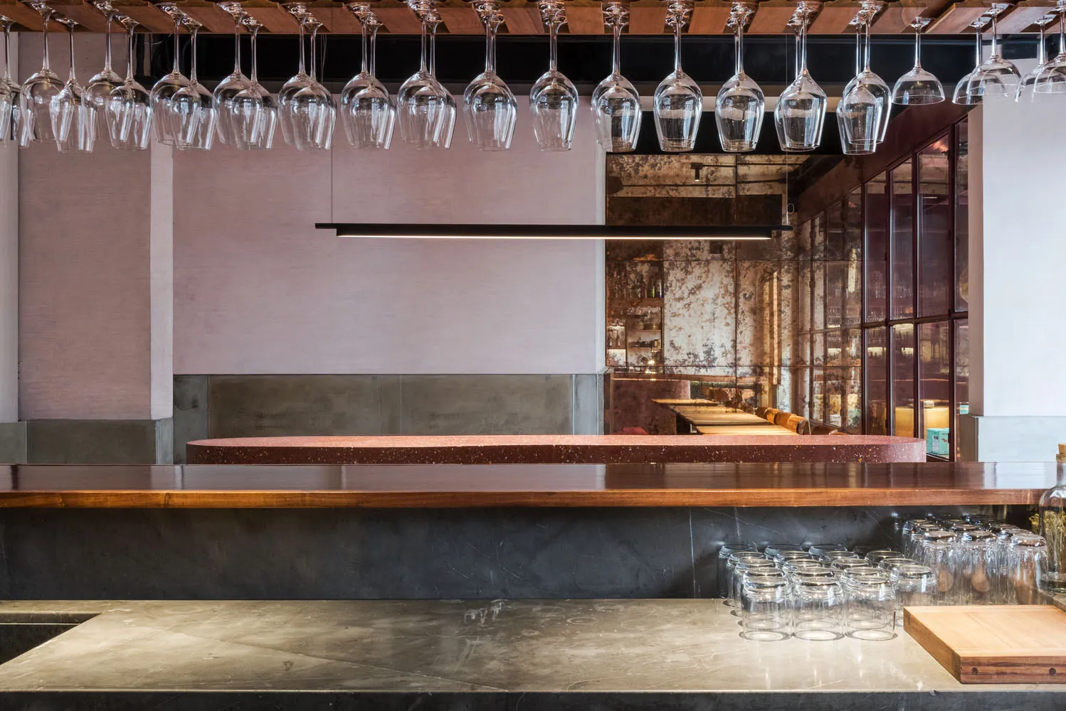 Industrial-style bar with terrazzo countertop and hanging wine glasses.