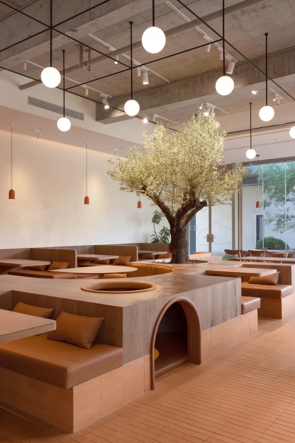 Modern cafe with minimalist design, concrete and wood materials, and a central tree.