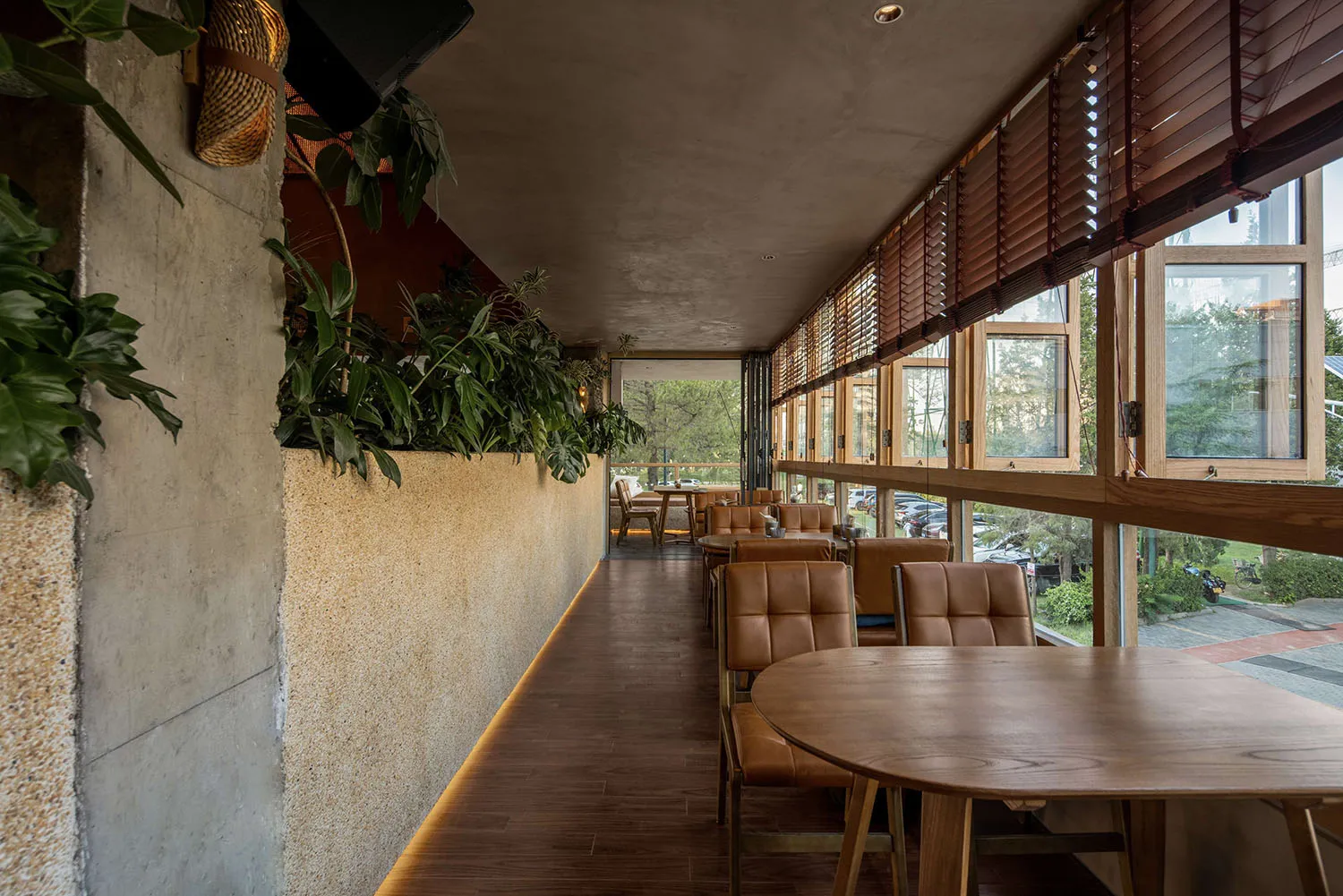 Industrial-style restaurant interior with wooden furniture and greenery.