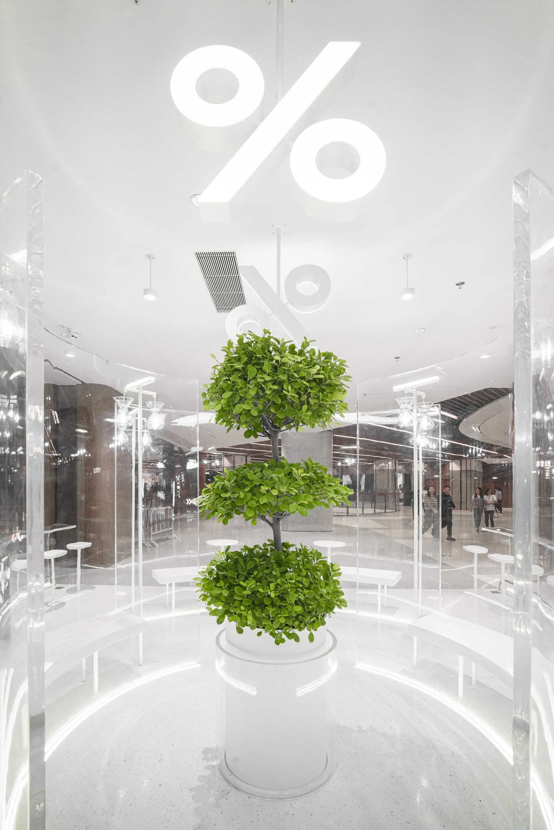 A modern shopping mall interior with minimalist design, featuring glass and concrete materials.