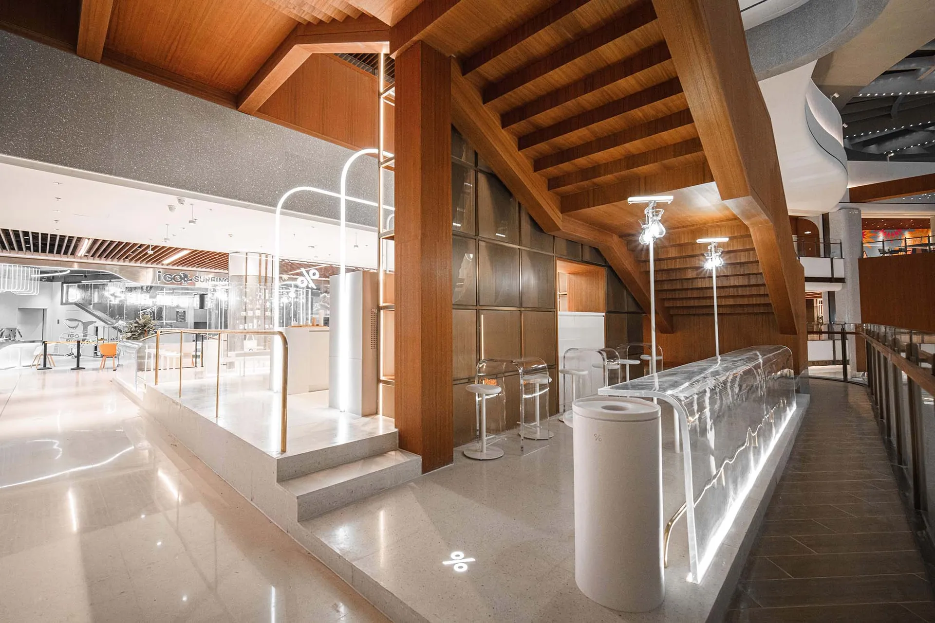 Modern interior design featuring wooden beams, acrylic furniture, and marble countertops within a coffee shop setting.
