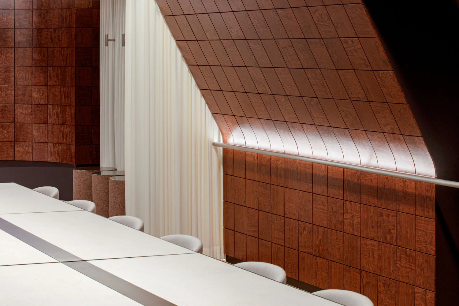 A modern conference room with wooden panels and white tables.