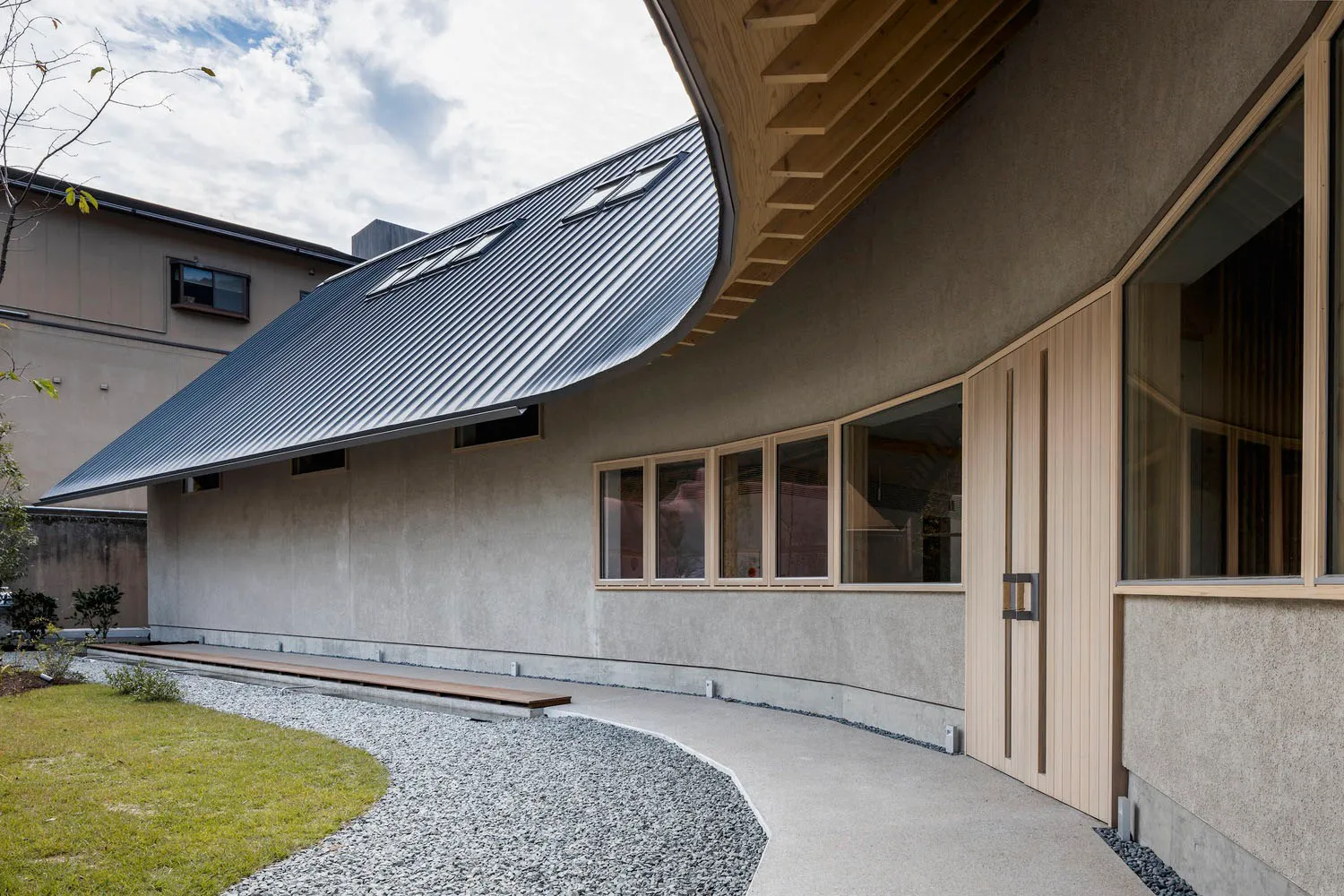 Modern metallic-clad building with curved roof and wood accents.
