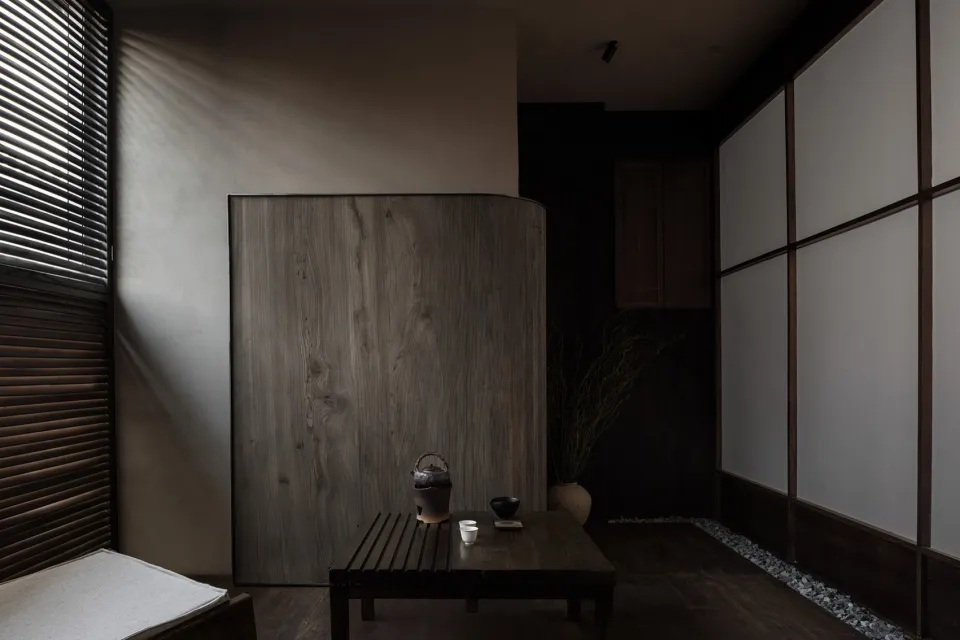 A minimalist tea room with wooden elements and a rustic teapot on a table.