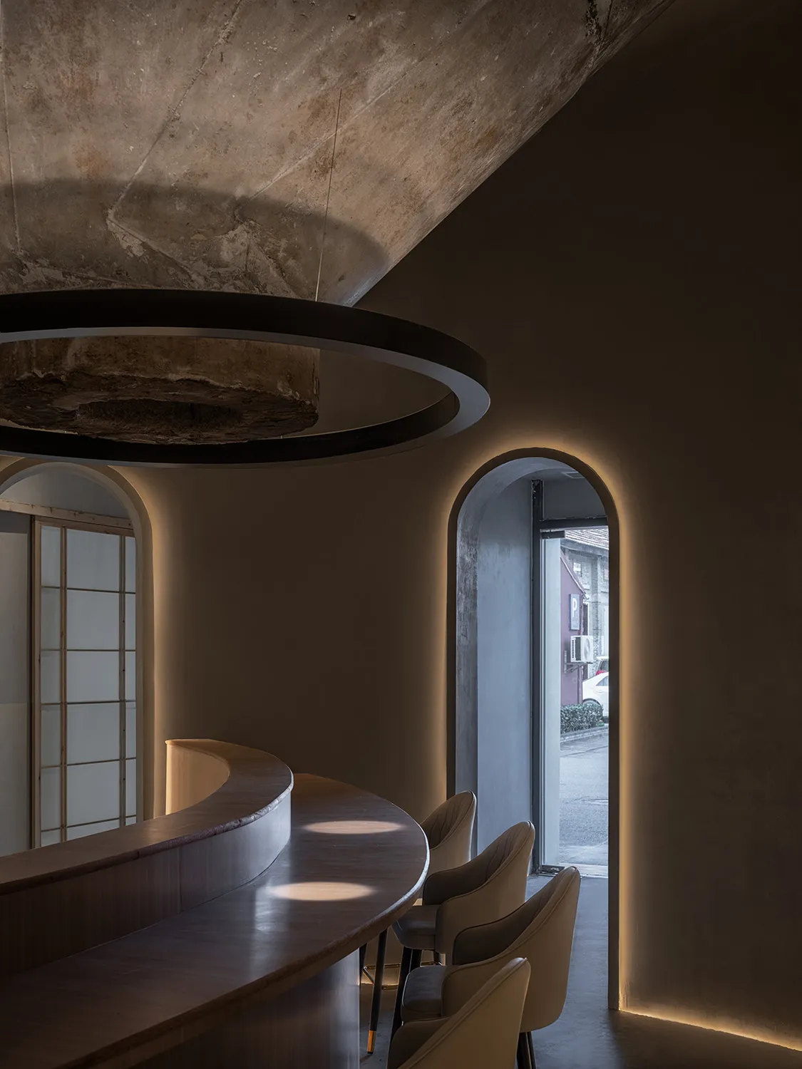 A modern restaurant bar featuring circular concrete elements and a sleek, minimalist design.