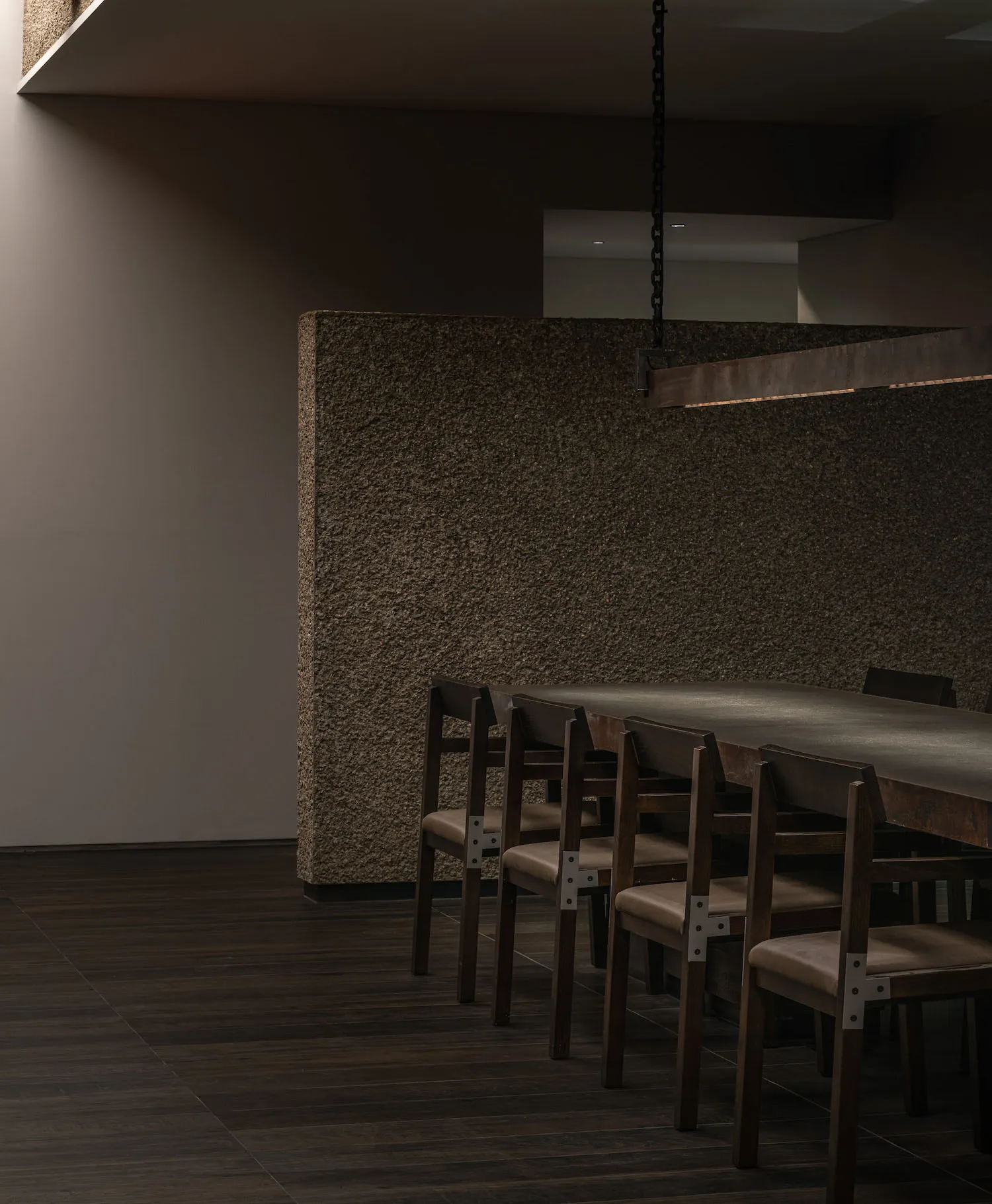 Modern dining room featuring a concrete table and chairs against a textured wall.