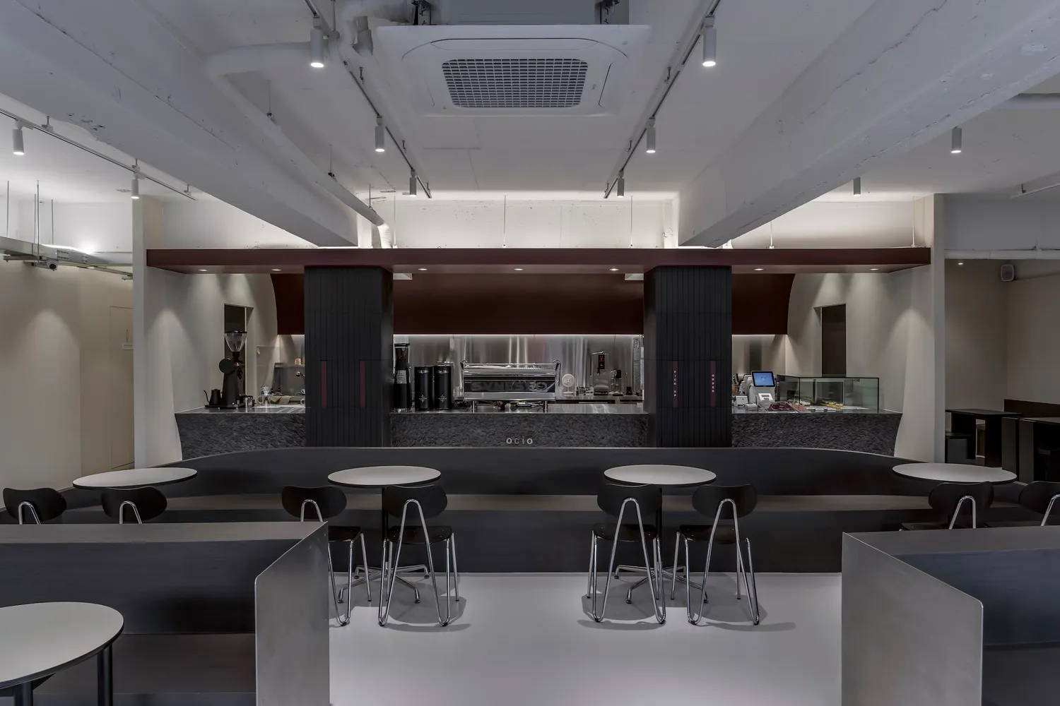 An industrial-style cafe with a metal bar counter and white counter tops.