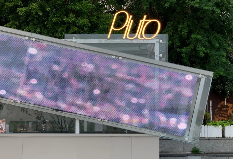 Neon Pluto sign and digital display on an exterior storefront extension
