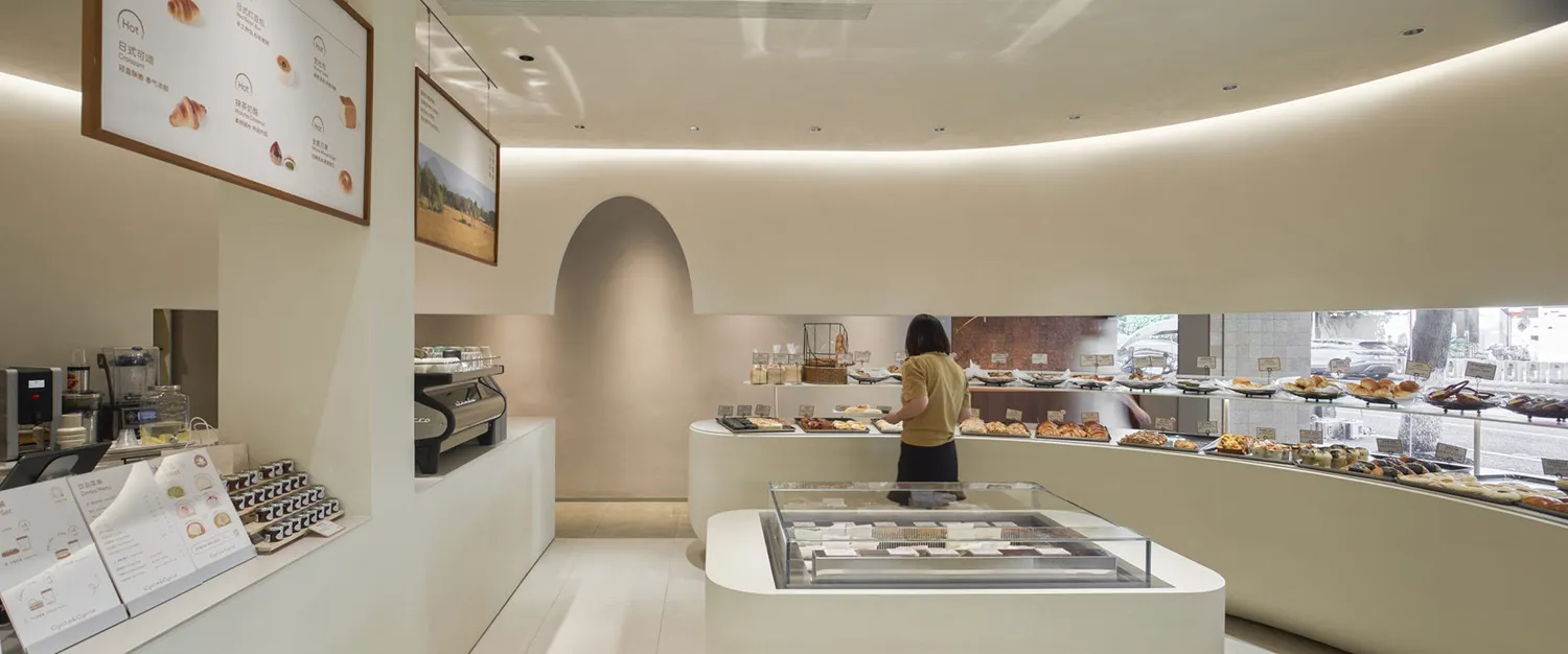 Interior of a modern bakery shop featuring white marble finishes and a selection of baked goods.