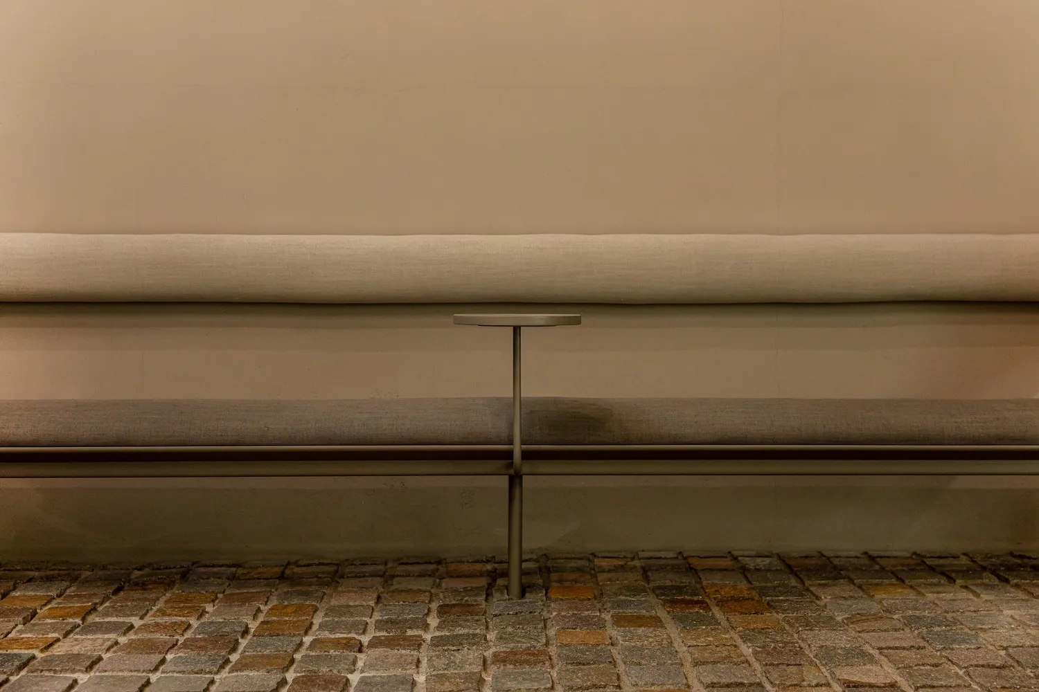 Contemporary design bench made of fabric seated on a concrete floor with a metal frame.