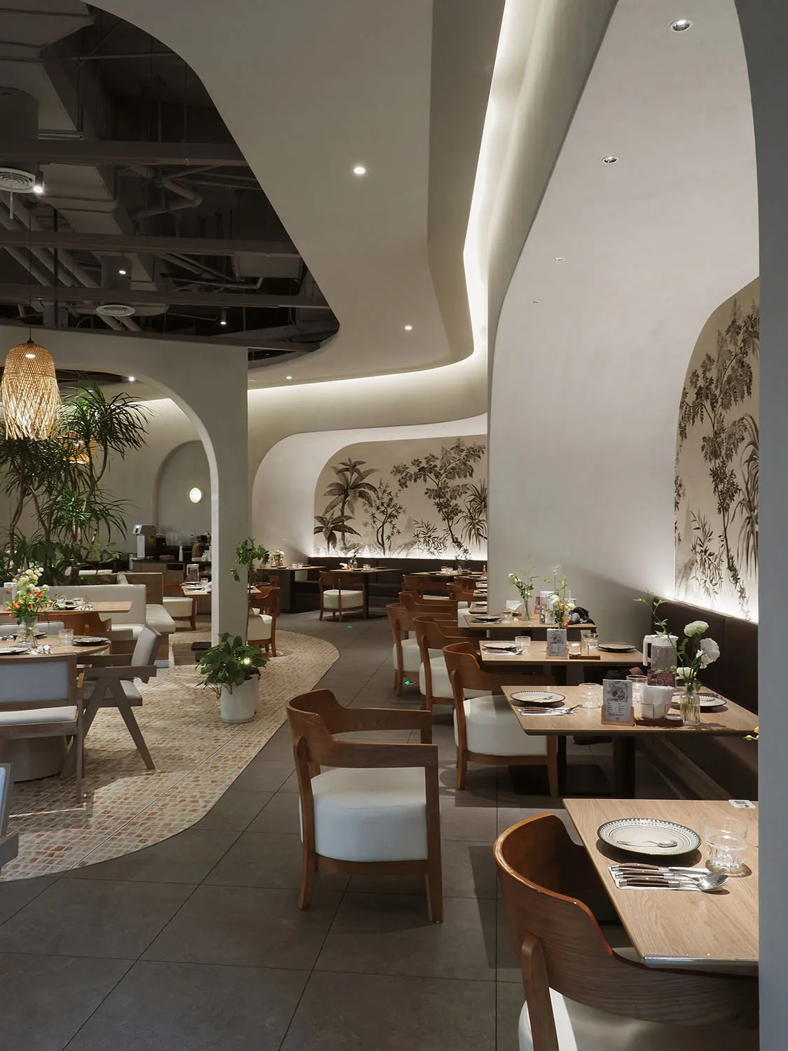 Restaurant interior with modern design, white plaster walls, wooden furniture, and hanging lights.