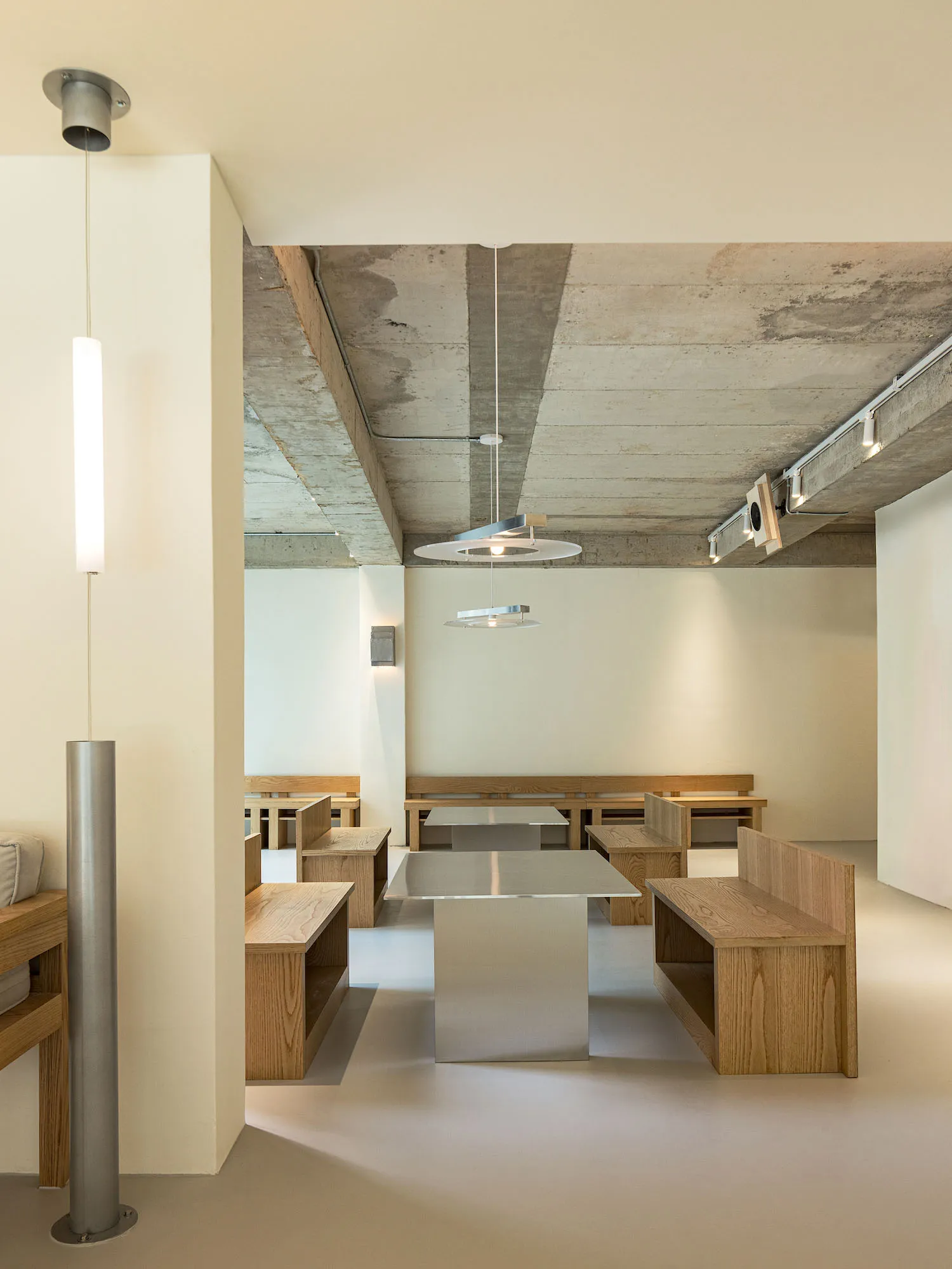 Modern minimalist restaurant interior featuring wooden benches and tables.