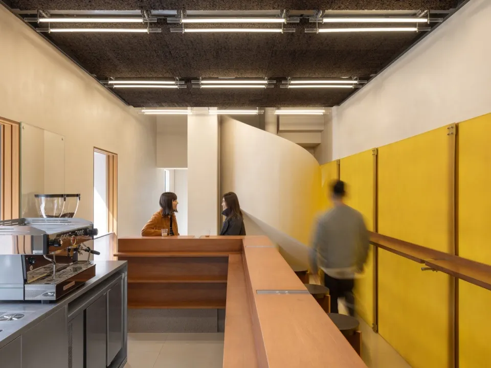 A modern coffee shop interior with yellow walls and a wooden counter.