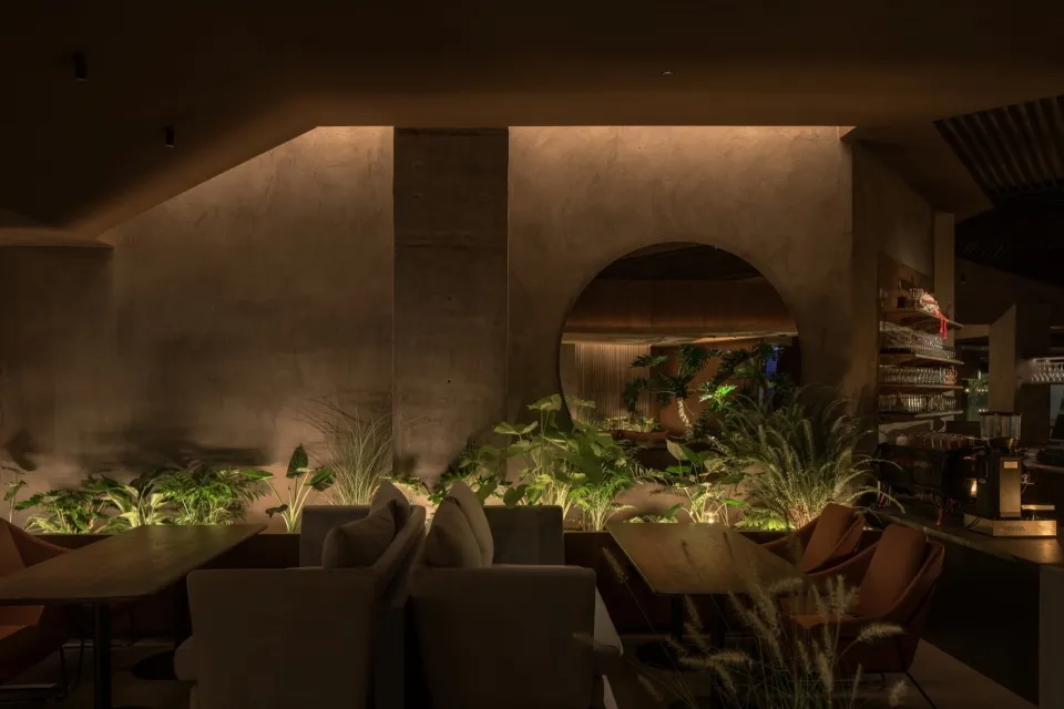 現代工業風餐廳，混凝土牆面搭配木質餐桌，搭配茂盛綠植營造溫馨氛圍。