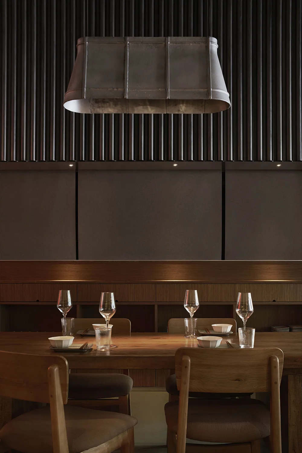 A rustic, industrial-themed restaurant interior with wood furniture, metal accents, and dark, dramatic lighting.