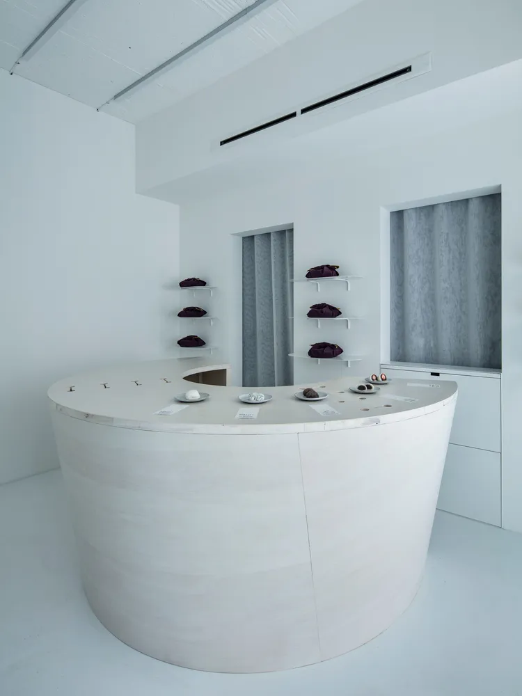 A minimalist retail space with a concrete countertop featuring small plates of food and accessories.
