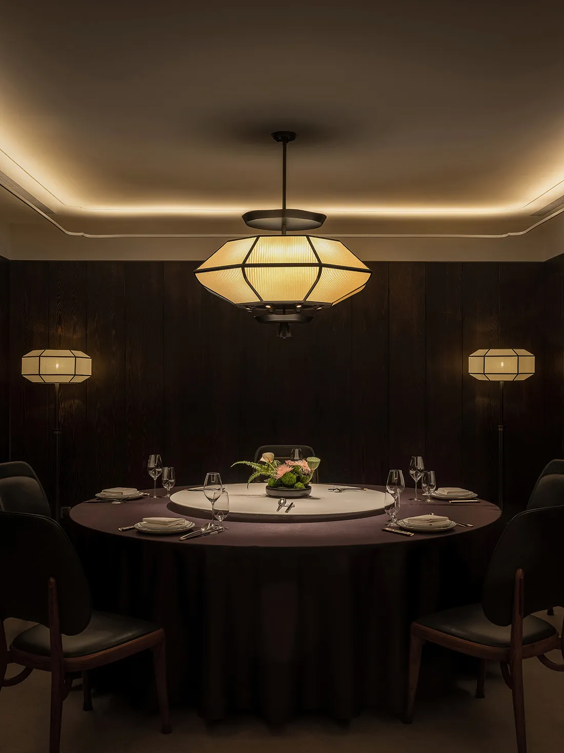 A well-lit, modern restaurant dining room with wooden paneling, a round table, and elegant decor.