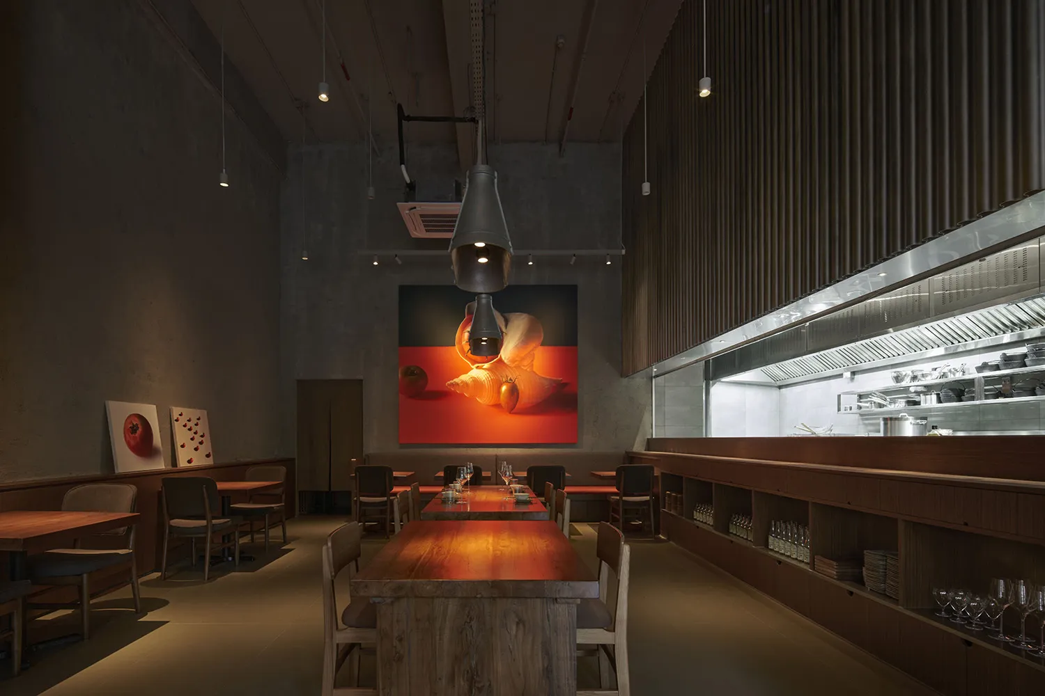 Modern restaurant interior with long wooden tables and metallic elements, featuring a minimalist design with large artwork on
