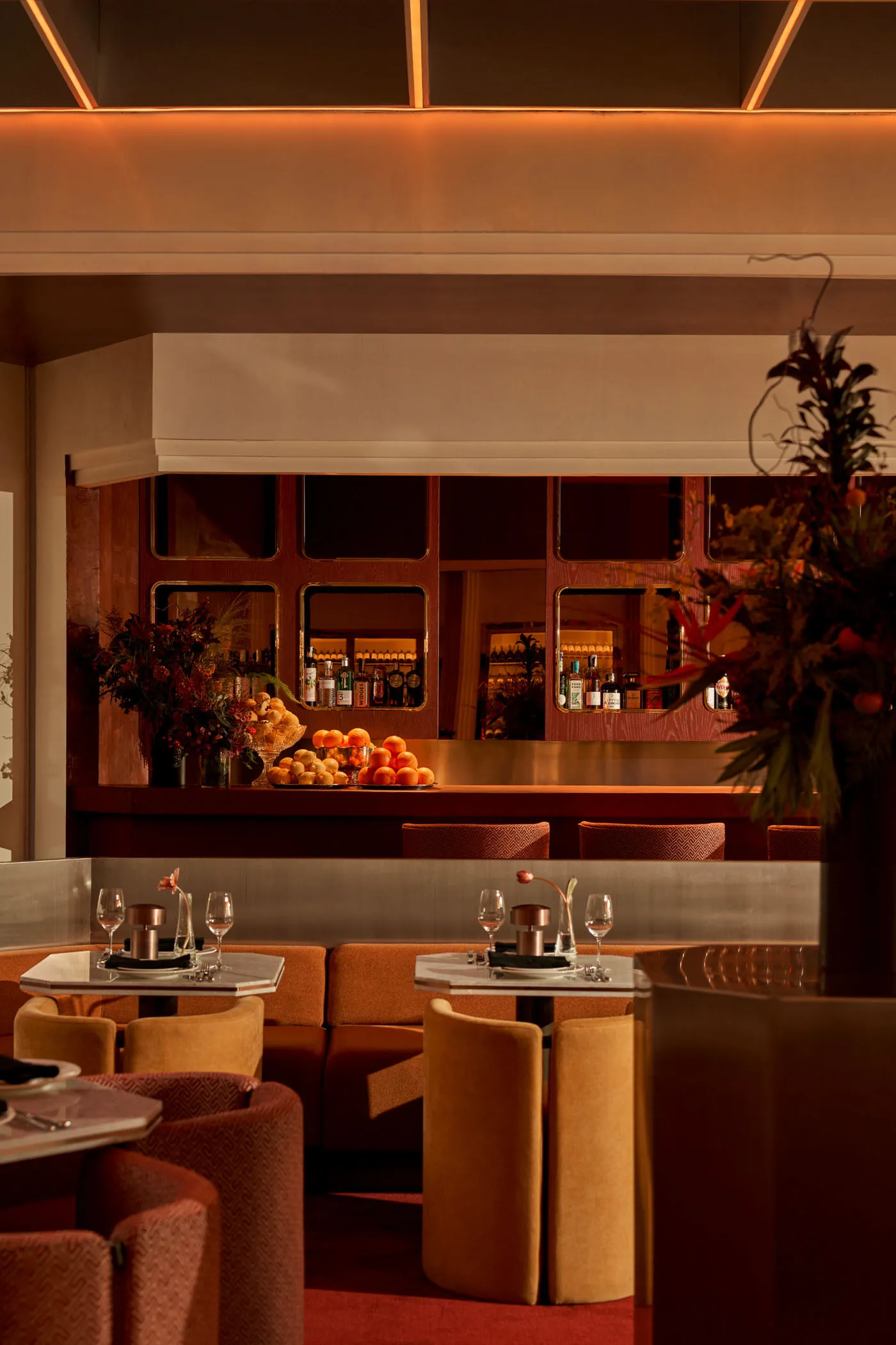 A modern restaurant bar with metal tables, leather seating, and walnut accents.