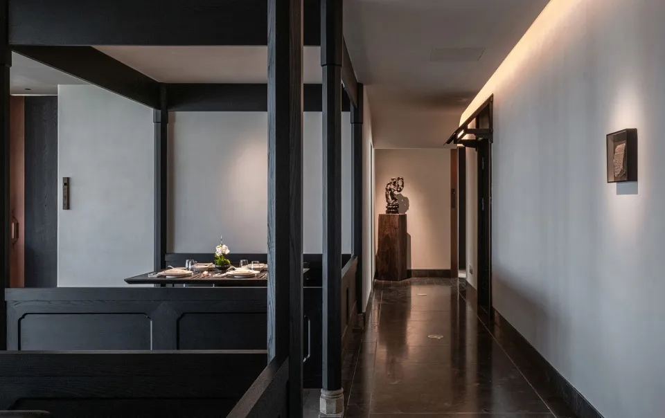 A minimalist dining room with dark wooden tables and chairs, clean lines, and a single flower arrangement on the table.
