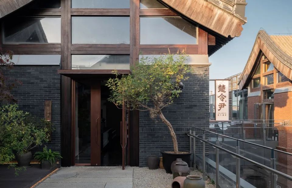 現代餐廳外觀，採用磚牆與混凝土材質，搭配黑色磚塊與盆栽樹木。