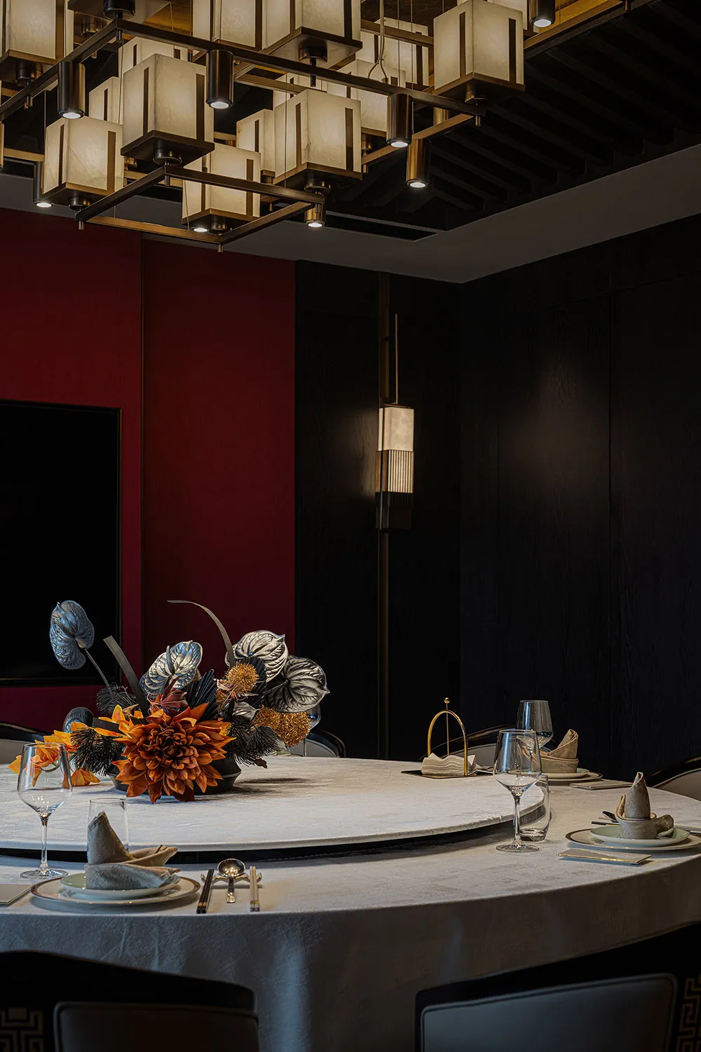 Modern, sleek restaurant dining area with circular table, contemporary lighting, and floral centerpiece.