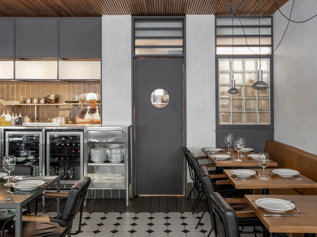 Industrial-style restaurant interior featuring metal cabinets, glass walls, and concrete floors