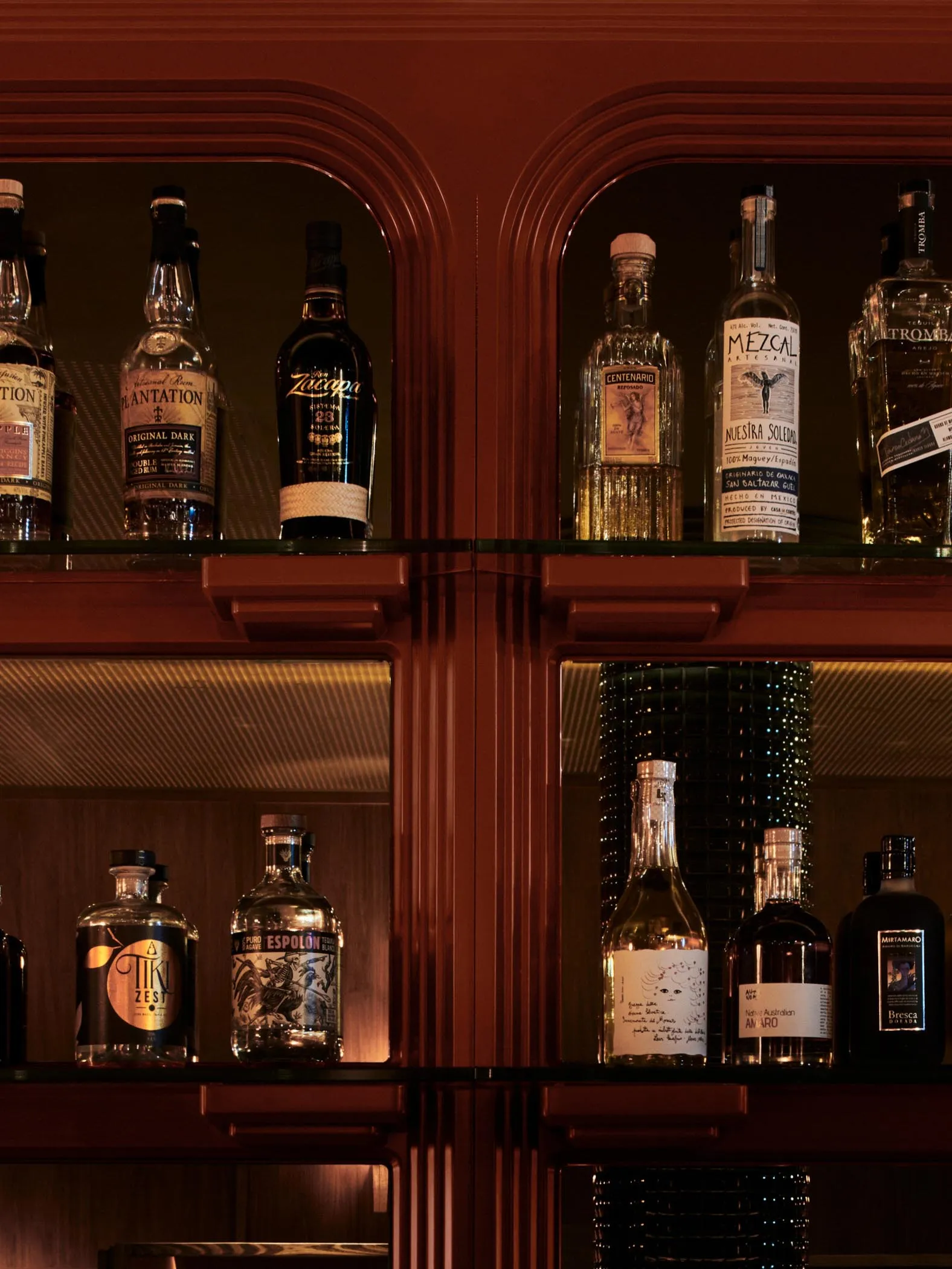 Modern bar shelves with a wooden finish, showcasing a variety of liquor bottles.