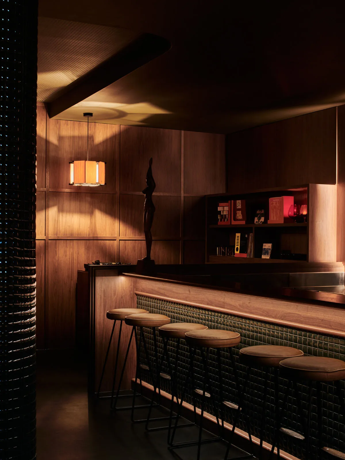 Modern retail bar with wooden panels, leather stools, and metal accents.