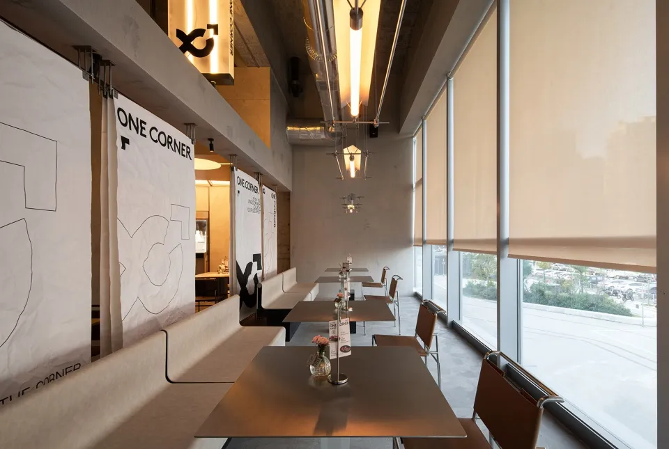 A modern industrial restaurant with metallic furniture, large windows, and minimalist decor.