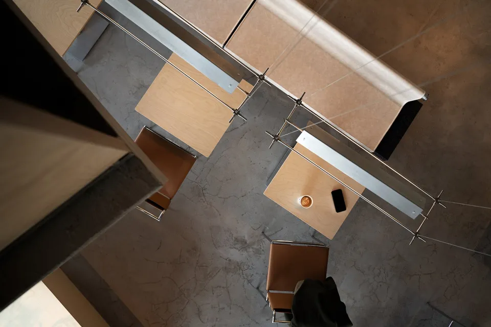 Modern office space with a wooden desk and chair, featuring a cup of espresso and a smartphone on the desk.