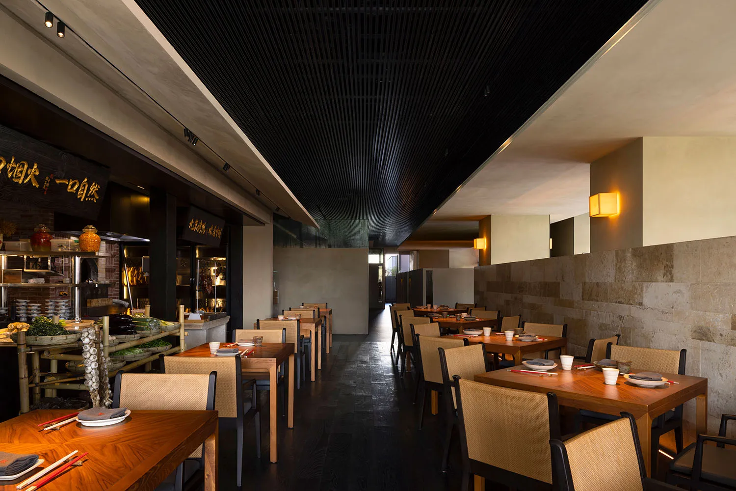 Modern restaurant interior with wooden tables, concrete flooring, and brick accents.