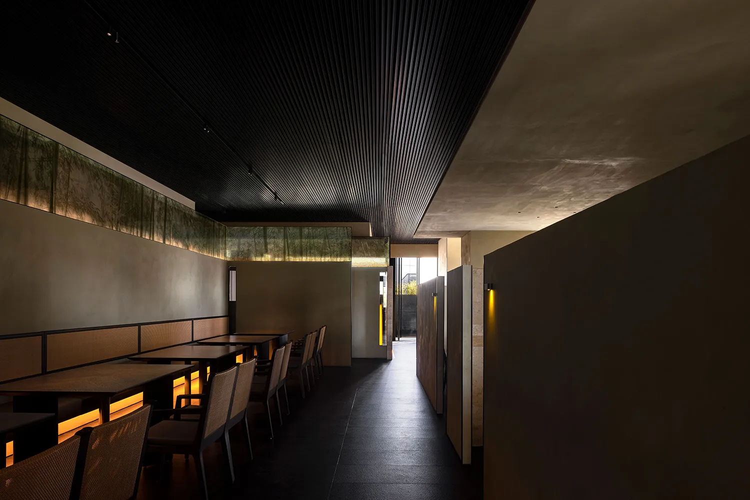 現代餐廳室內,配有木質餐桌、混凝土牆面及溫暖燈光。