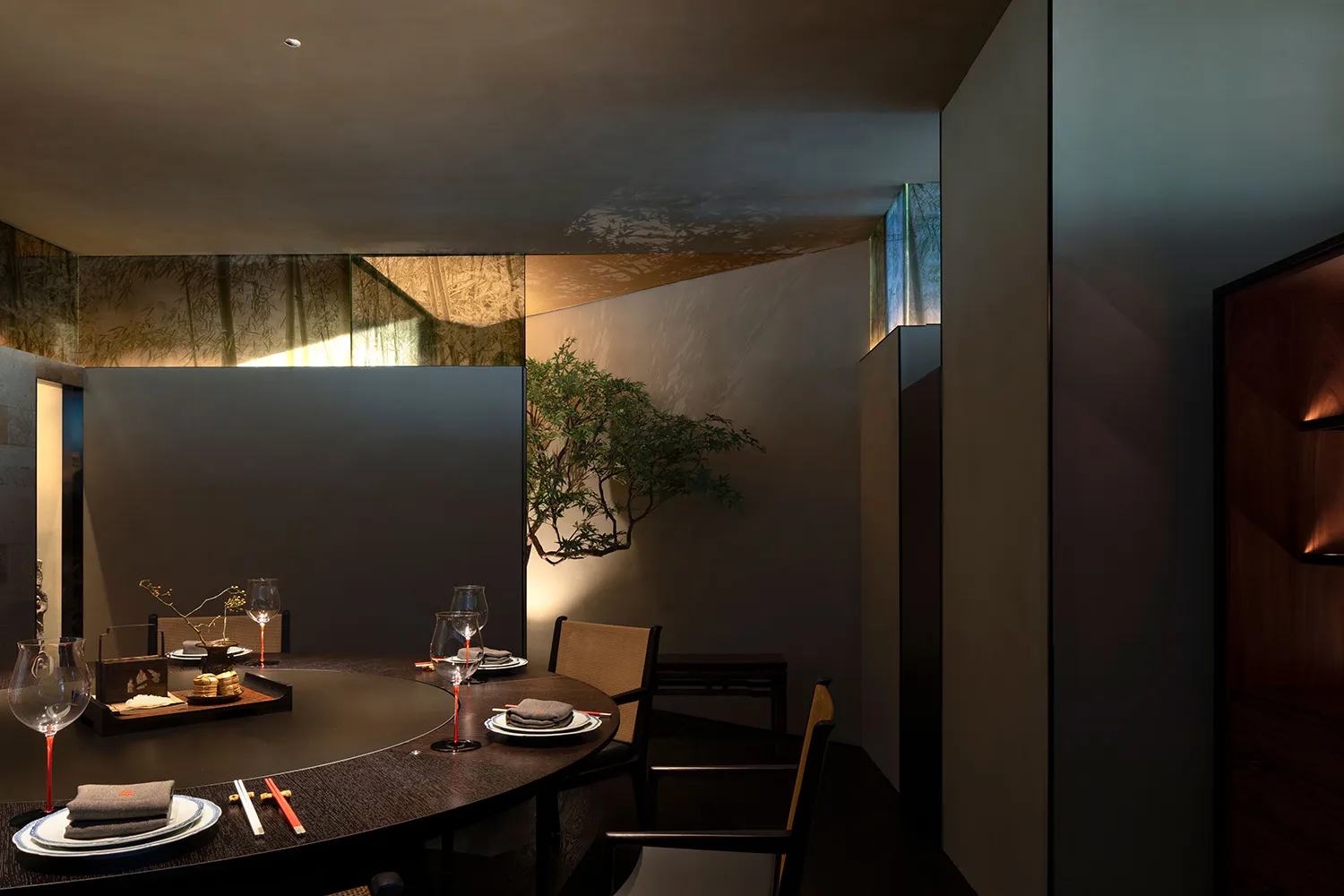 Circular dining table surrounded by chairs in a minimalist restaurant setting.
