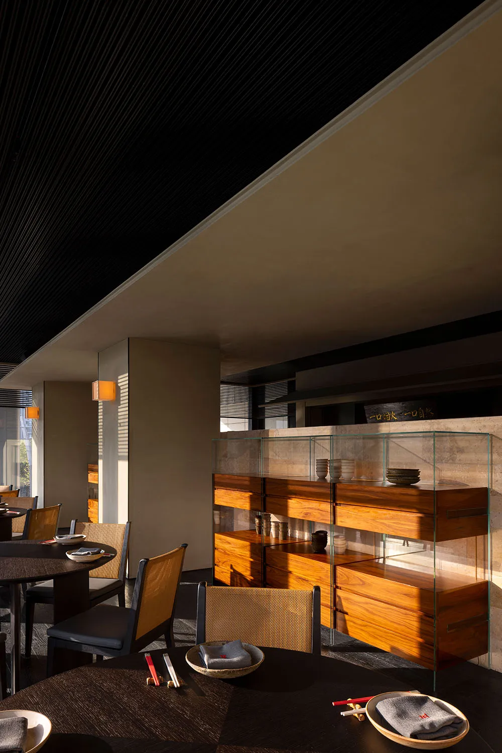 The interior of a modern restaurant featuring minimalist design in wood, glass, and wicker materials.