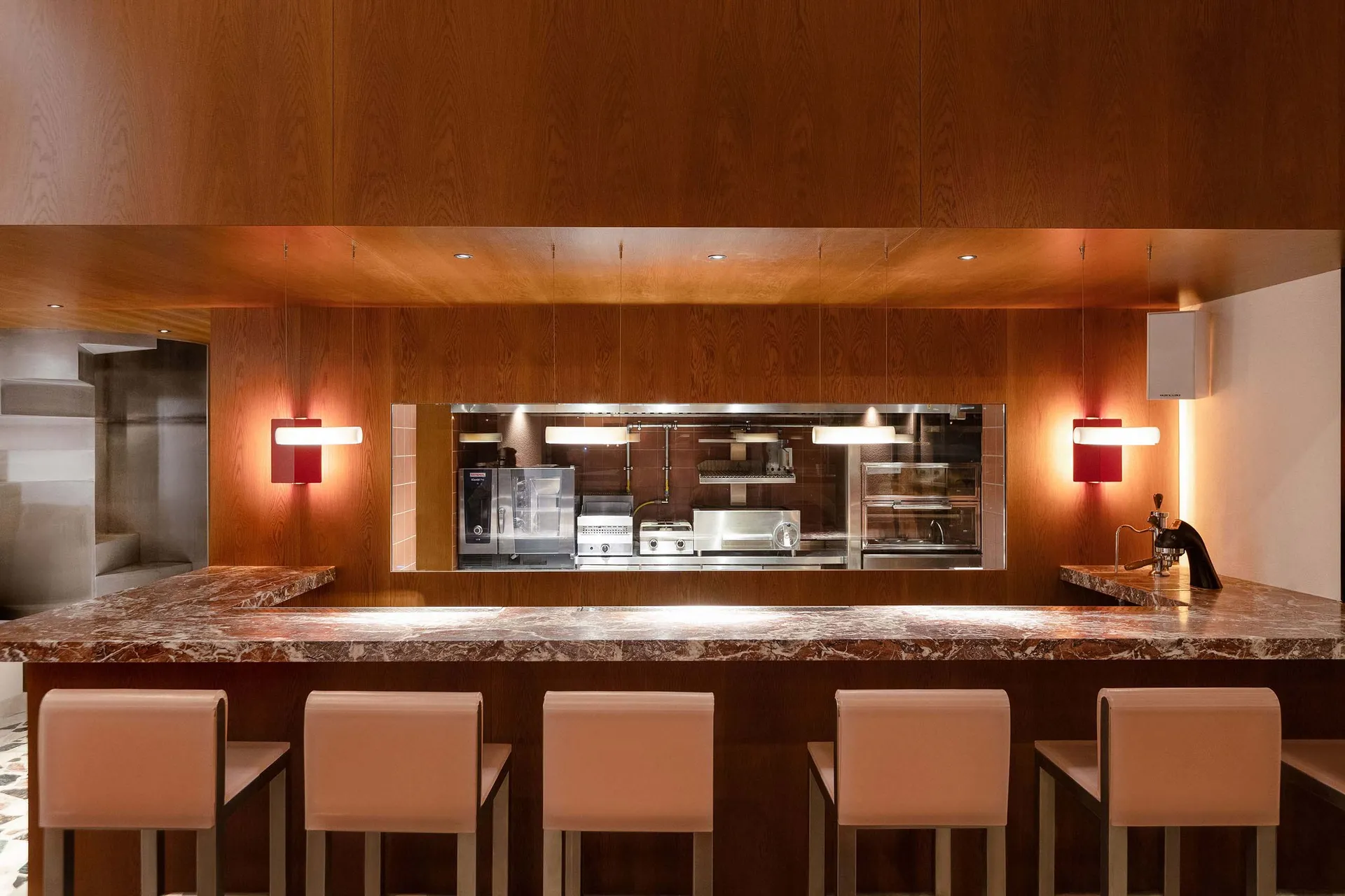 A modern minimalist restaurant bar with a marble countertop and stools.