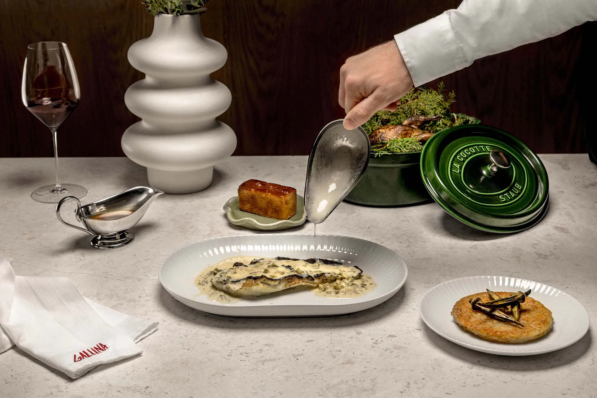 現代餐飲場景,展示陶瓷餐具、綠色陶鍋以及一杯紅酒。