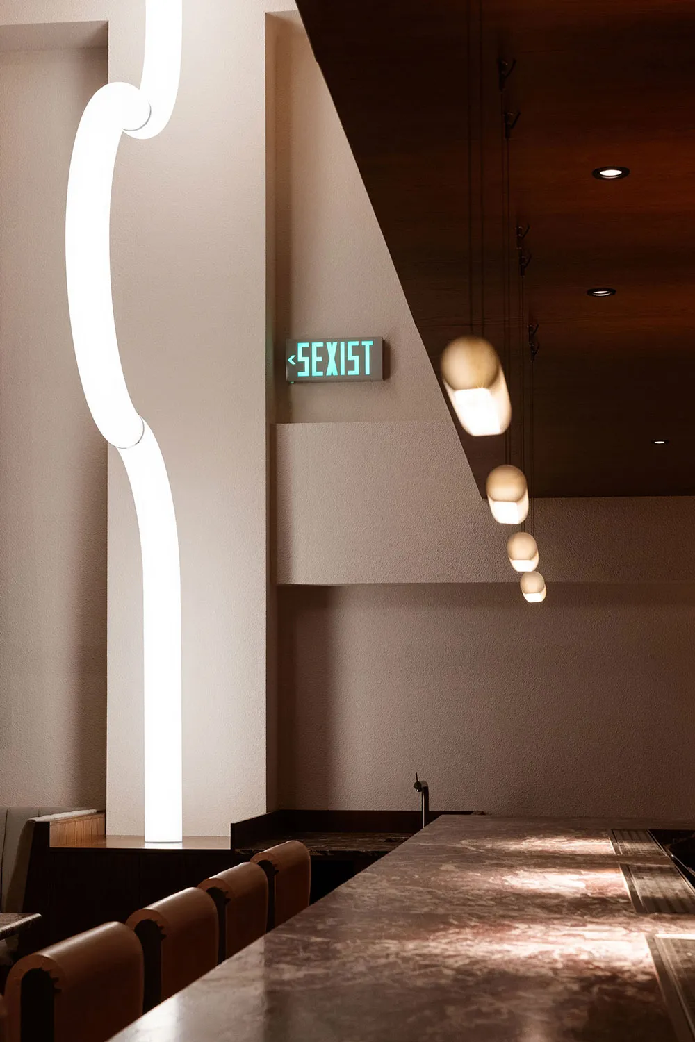 Modern restaurant interior with minimalist design, featuring sleek white walls, contemporary lighting, and a long countertop.