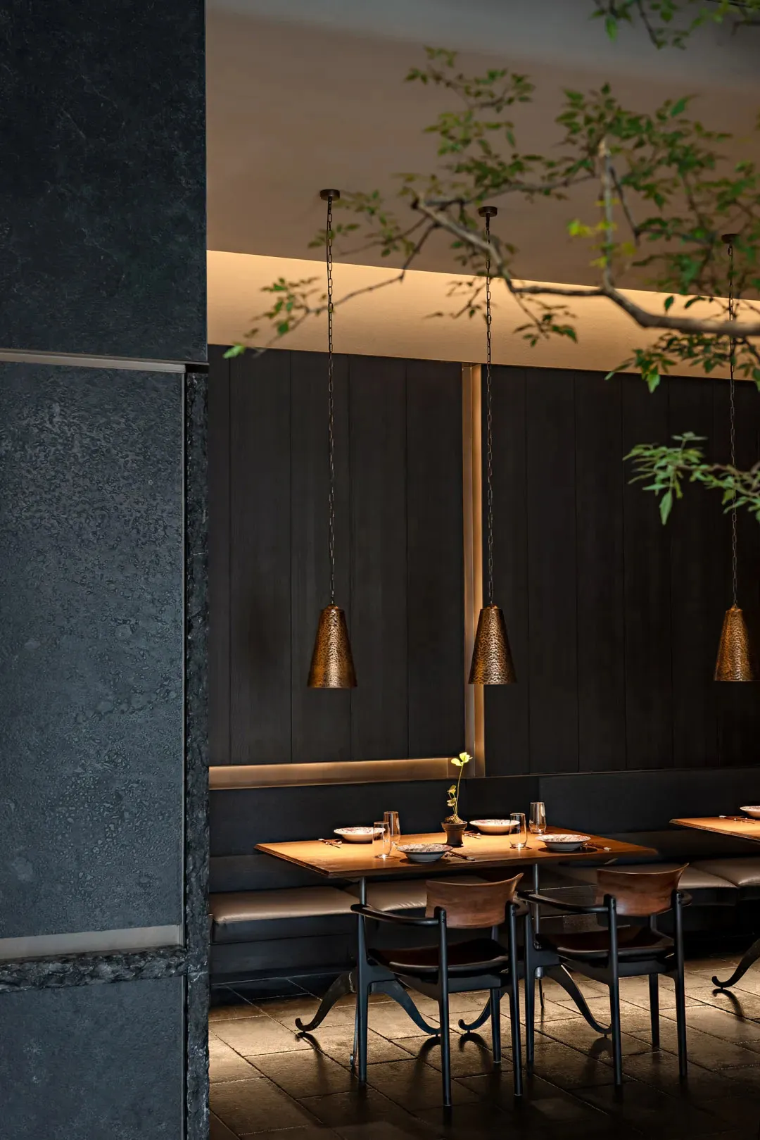 Industrial style restaurant dining room with black metal pendant lights, wooden tables, and leather seats.