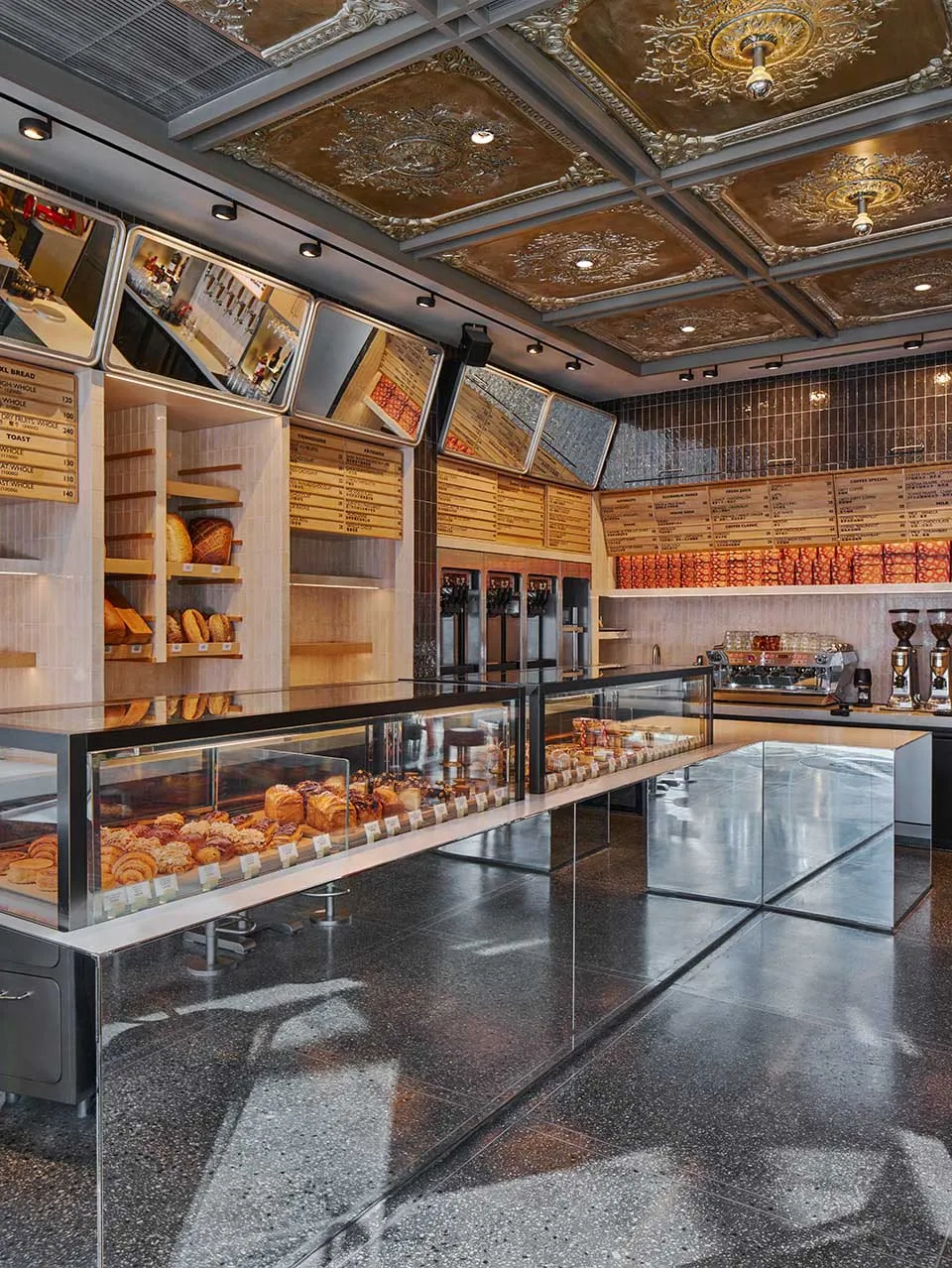 Modern coffee shop with a display case showcasing an assortment of pastries and breads, illuminated by overhead lighting.