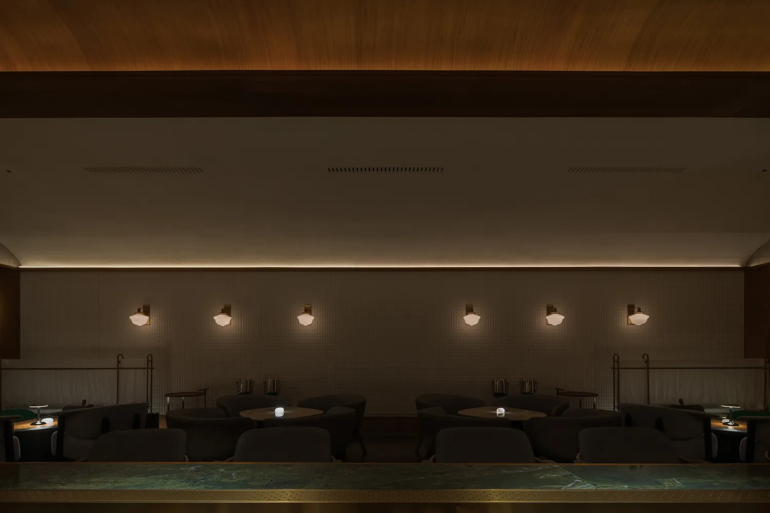 A modern restaurant bar with concrete walls and lighting fixtures.