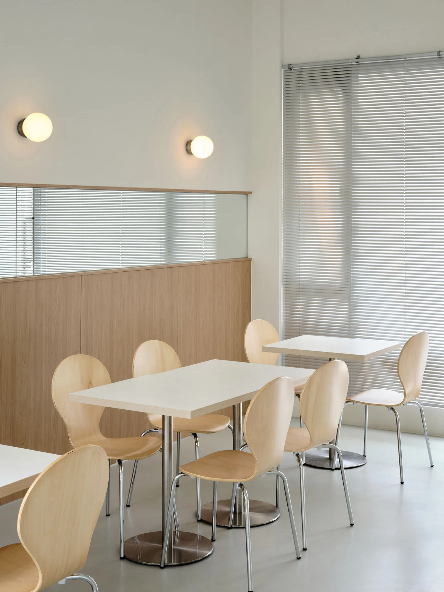 A modern cafe interior with wooden furniture and white tables.