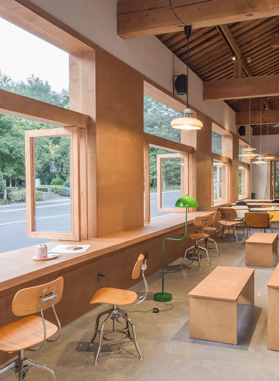 A modern cafe interior with large windows and wooden seating.