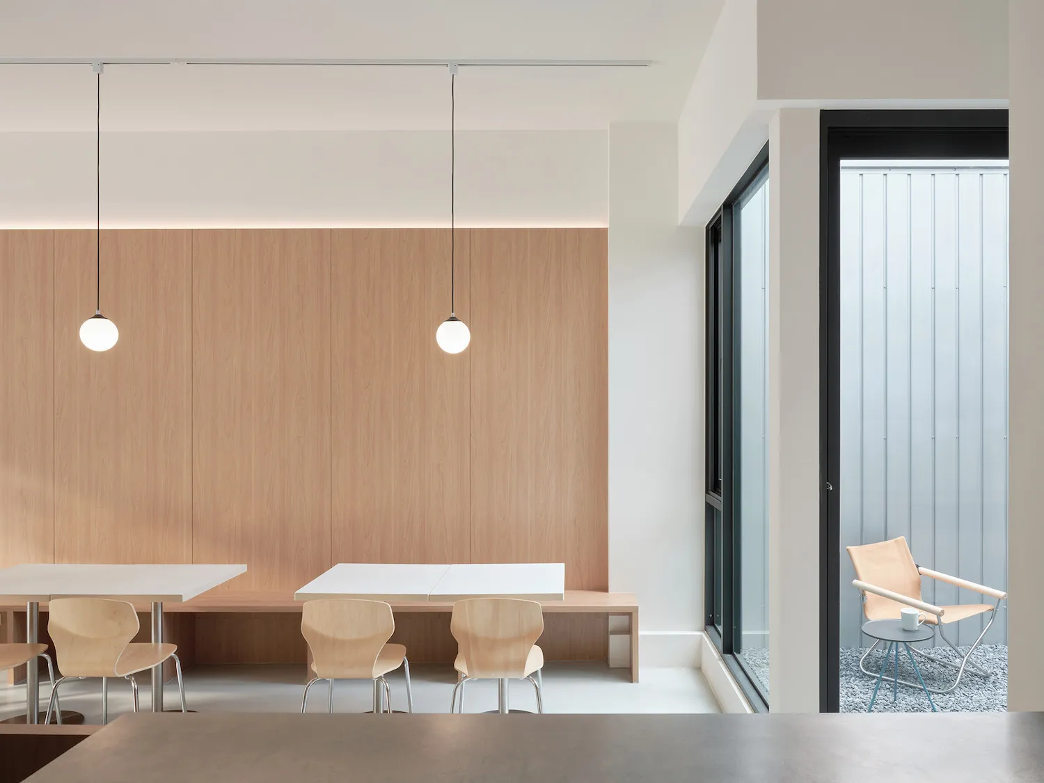 Contemporary office space featuring minimalist design with wooden furniture, concrete flooring, and glass partitions.