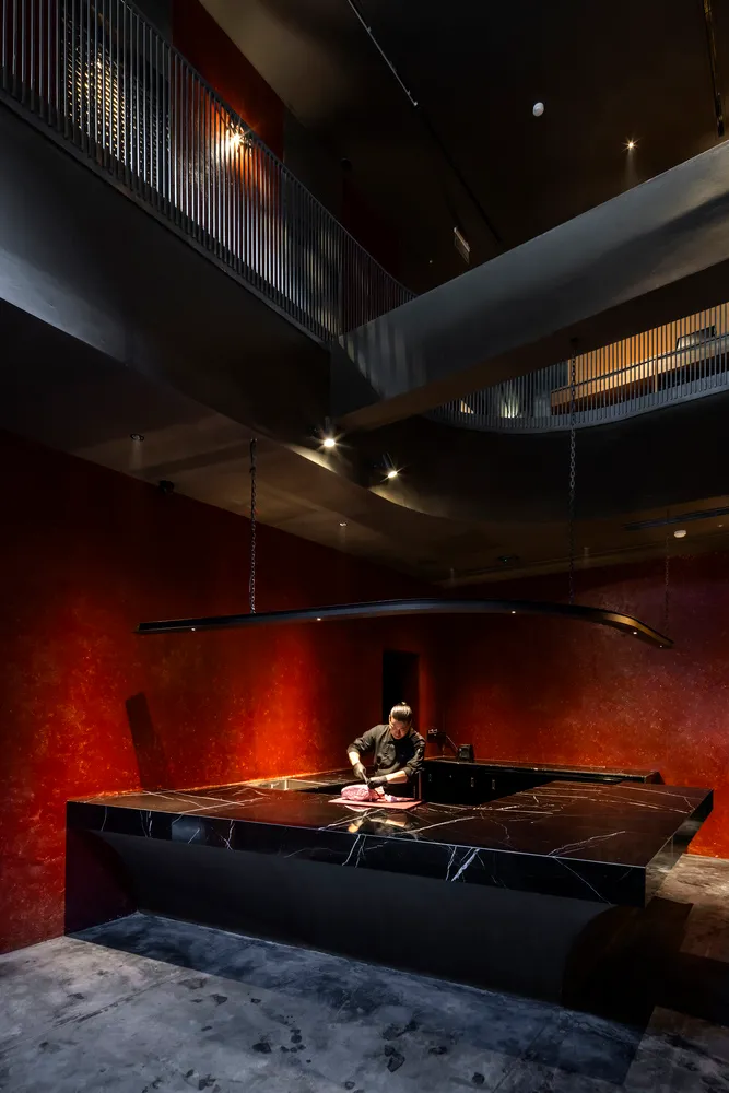 A modern restaurant kitchen with a black marble countertop and red walls.