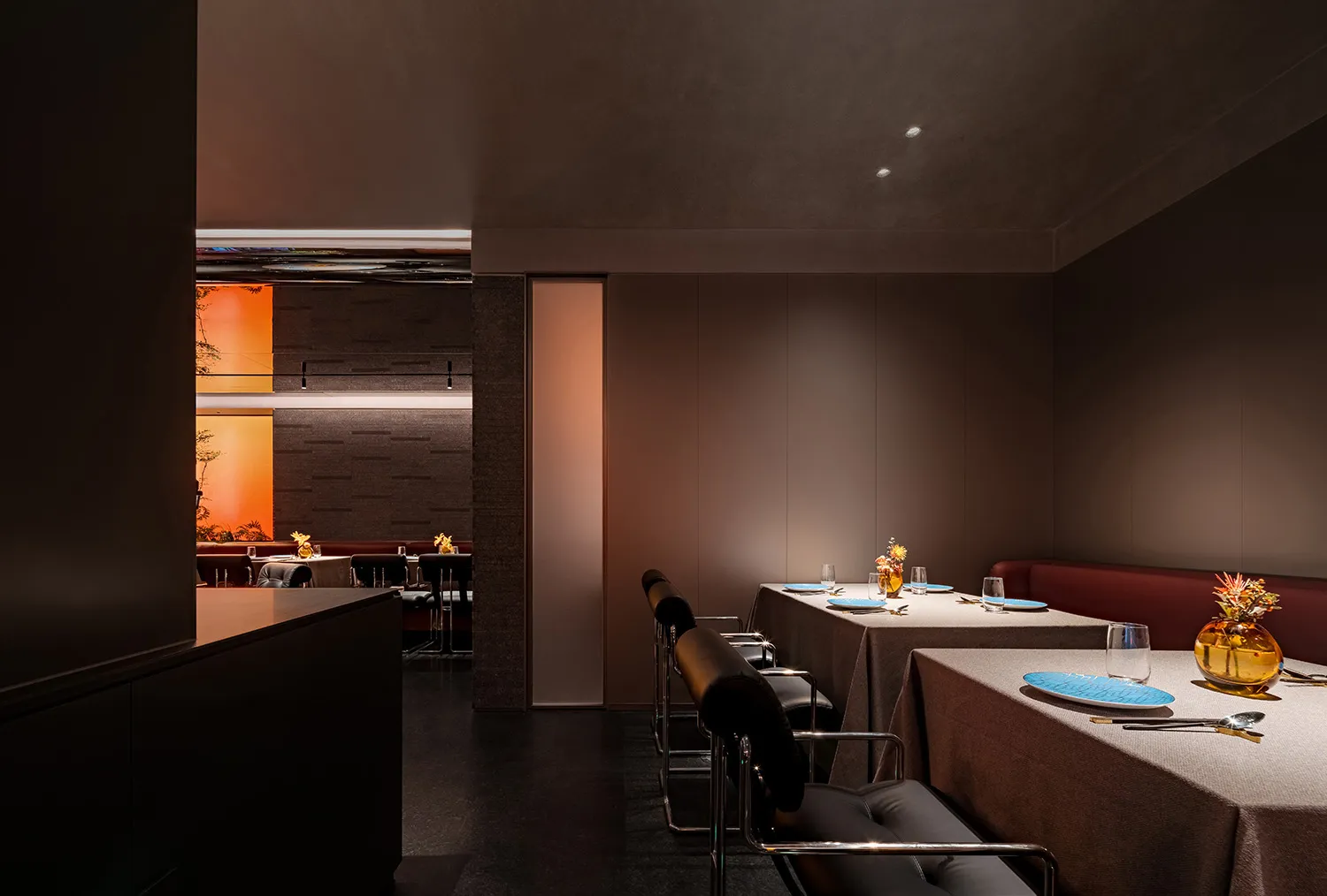 A modern restaurant interior with textured materials, featuring tables, chairs, and decorative elements.