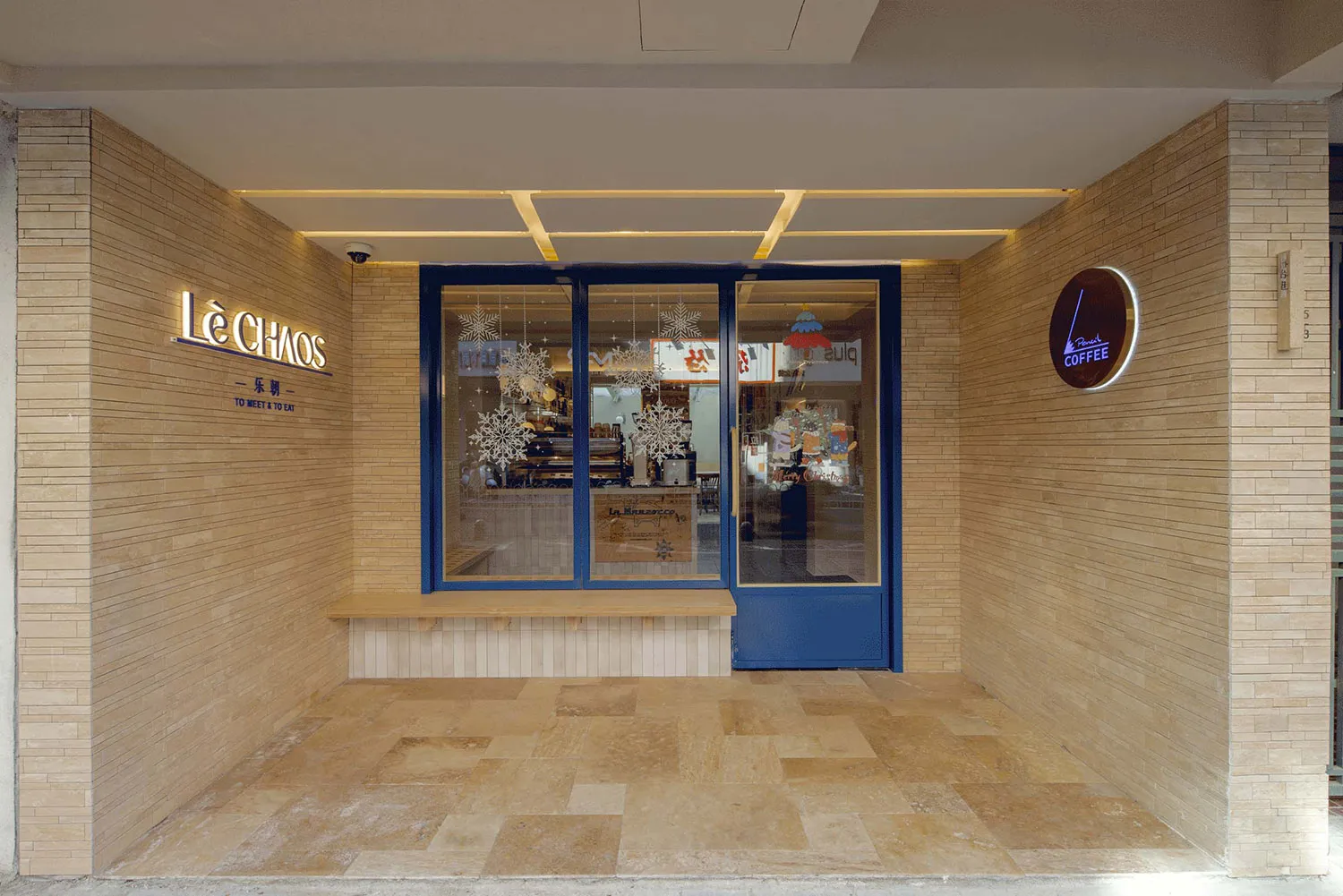 A cozy coffee shop with a brick wall, glass doors, and interior decor visible through the glass.