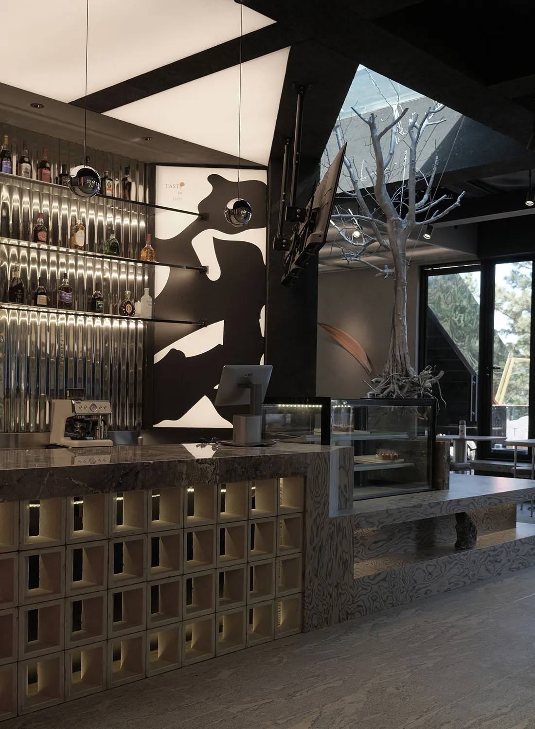 A modern coffee shop with a sleek marble interior featuring a bar counter and a tree in the center.